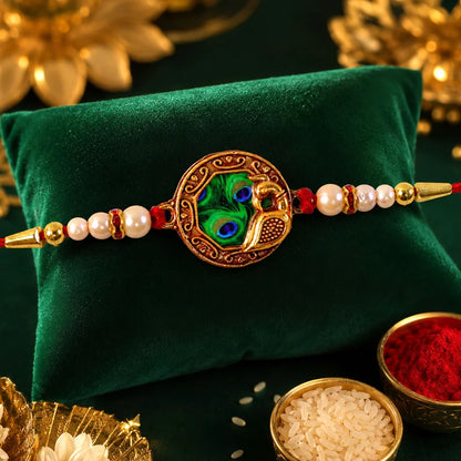 Elegant Rakhi With Peacock Feather Design And Pearl Bead Accents On Red Thread