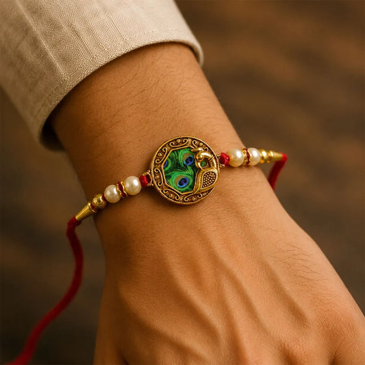 Elegant Rakhi With Peacock Feather Design And Pearl Bead Accents On Red Thread